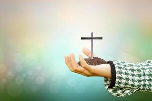 Human hand holding cross on blurred nature background. photo