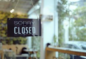 Business coffee cafe shop sign board is hang on door and show Sorry We are Closed with cafe and resturant blur bokeh background. photo