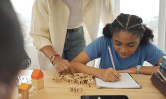 profesora afroamericana de pie con alumnos enseñando lecciones de escritura en un aula moderna. foto