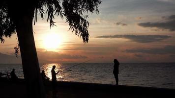 silueta de dos novias filmando imágenes maravillosas de puesta de sol en la playa de teléfonos móviles. video