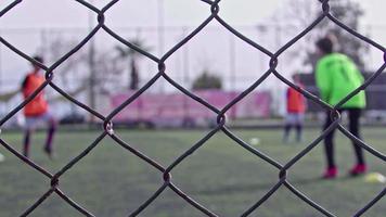 jugadores de fútbol entrenando detrás de imágenes oxidadas de vallas metálicas viejas. video