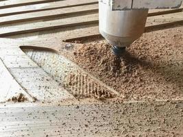 proceso de trabajo de la máquina láser cnc en la puerta de madera para hacer ranuras por control informático. enfoque selectivo. foto