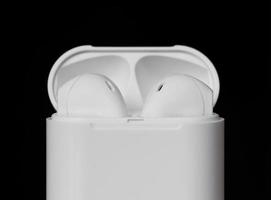 Close up white color true wireless earphone in charging case isolated on black background. Selective focus.