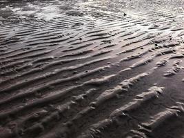 la marea baja natural muestra el patrón de ondas de arena en la playa al atardecer. enfoque selectivo. foto