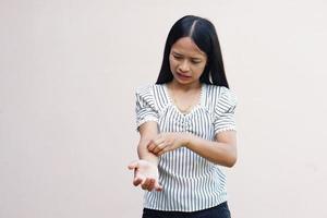 Woman scratching arm from itching on light gray background. Cause of itchy skin include insect bitesConcept of health care skin. photo