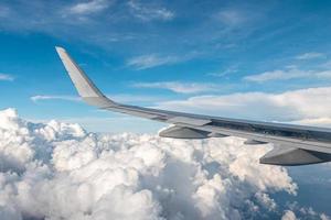 Large commercial airplane wing curving. The blue skyline view above the clouds from air plane window. photo