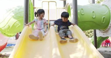 Cute boy and friend are having fun playing with the yellow slide. They are happy with the rides at the playground. video