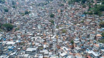 Aerial view of Favela da Rocinha, Biggest Slum in Brazil on the Mountain in Rio de Janeiro, and Skyline of the City behind photo