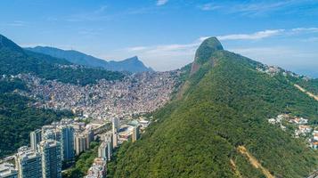 Aerial view of Favela da Rocinha, Biggest Slum in Brazil on the Mountain in Rio de Janeiro, and Skyline of the City behind photo