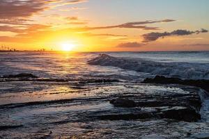 Scenic sunset over the sea. The sun sets on the water. Clouded sky is painted with bright colors. Sunset beach in a summer evening. Brazil. photo