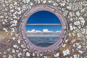 Peephole of boat with blue sea. photo