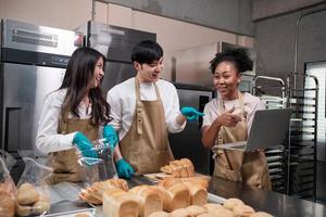 Three young friends and startup partners of bread dough and pastry foods busy with homemade baking jobs while cooking orders online, packing, and delivering on bakery shop, small business entrepreneur photo