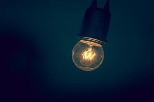 Retro light bulb hanging with dark space background for your decoration, concept of creativity - vintage color filter photo