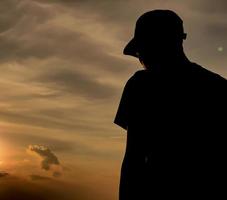 silhouette of a man wearing a hat at sunset photo