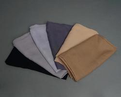 Stacks of nude colored veils neatly arranged on a gray background. Thin fabric blend of gray color that is ready to be used for Muslim women. Can also be used for sales displays. focus blur. hijab. photo