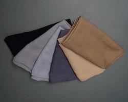 Stacks of nude colored veils neatly arranged on a gray background. Thin fabric blend of gray color that is ready to be used for Muslim women. Can also be used for sales displays. focus blur. hijab. photo