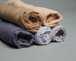 A roll of nude colored veil is neatly arranged on a gray background. Rolls of thin gray fabric that are ready to be used for Muslim women. Can also be used for sales displays. focus blur. hijab women. photo