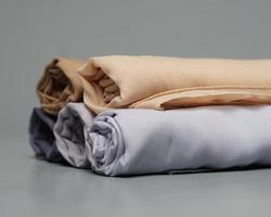 A roll of nude colored veil is neatly arranged on a gray background. Rolls of thin gray fabric that are ready to be used for Muslim women. Can also be used for sales displays. focus blur. hijab women.