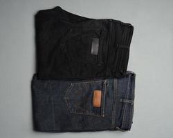Stacks neatly arranged blue and black jeans. Contemporary pants are often used as a fashion choice for today's people. Jeans are durable and not easily damaged. long pants mockup for design templates. photo