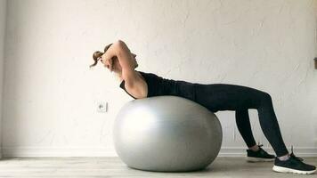 fitness, deportes y estilo de vida saludable. mujer joven haciendo ejercicio en casa con pelota de estabilidad o pelota de fitness. entrenamiento en casa video