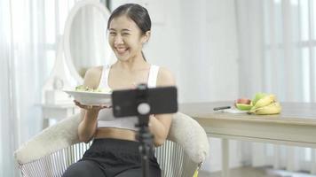 bloggerin führt online-kurs über gesunde ernährung durch und spricht in sozialen netzwerken vor der kamera. Fitness-Frau zeichnet das Training über vegetarische Kochdistanzen per Smartphone-Video-Tutorial auf