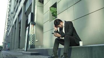 A stressed businessman was having a conversation on his smartphone in the street. Serious professional calling on a cellphone in slow motion. A portrait of an upset businessman receiving bad news video