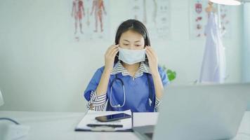 slow motion. vacker kvinna läkare som bär en mask sitter vid bordet på klinikkontoret på arbetstid video
