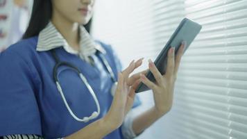 Ärztin, die eine digitale Tablet-Computer-App verwendet, die im Krankenhausbüro steht. junge frau, professionelle ärztin, die in der klinik ein touchscreen-pad-gerät hält. medizinisches tech-konzept für das online-gesundheitswesen.