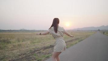 le donne asiatiche fanno surf con lo skateboard per le strade fuori dalla strada di campagna con vista sulle montagne la sera. concetto di stile di vita. video