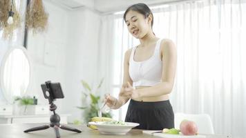 Female blogger leads online course on healthy eating, talking in front camera on social networks. Fitness woman records training on vegetarian cooking Distances diet through smartphone video tutorial