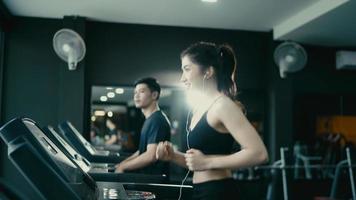 Athletic Sports Man And Woman Wearing Running on a Treadmill. Energetic Female Athlete Training in the Gym video