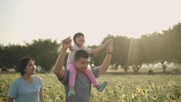 un padre asiático llevó felizmente a su hija al campo de girasoles. durante la puesta de sol
