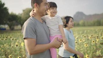 An Asian father happily took his daughter to the sunflower field. During the sunset video