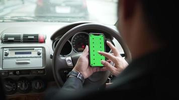 close-up handen van een zakenman met behulp van een smartphone, typen op een mock-up groen scherm in een auto tijdens files. chroma key voor groen scherm video