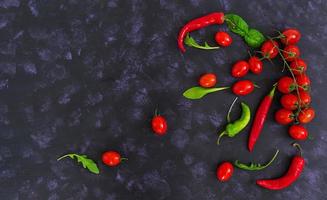 Fresh ripe cherry tomatoes and pepper on a dark background. Top view photo