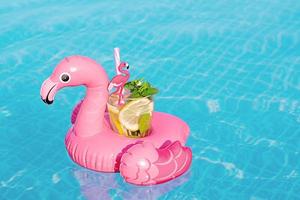 mojito de cóctel fresco en un juguete inflable de flamenco rosa en la piscina. concepto de vacaciones. foto