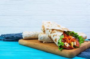 Delicious shawarma sandwich on wooden background photo