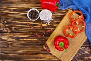 Pepper, tomato, salt, different spice on wooden background photo