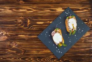 Grilled toast with asparagus in bacon and poached egg on wooden background photo