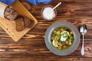 Russian soup solyanka with sour cream on wooden background photo