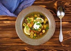 Russian soup solyanka with sour cream on wooden background photo