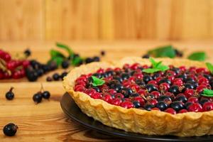 Delicious tart with custard and currant on wooden background photo