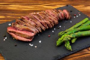 Grilled beef steak and asparagus on wooden background photo