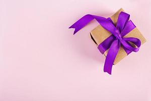 Gift box with purple ribbon isolated on pink background. Top view