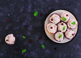 Lemon cupcakes with cherry cream. Cranberry, mint leaves. Food on a dark background. Top view