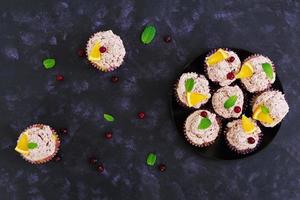 Lemon cupcakes with cherry cream. Cranberry, mint leaves. Food on a dark background. Top view photo