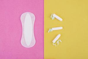 cuidado de la higiene durante los días críticos. elegir entre un tampón y una toalla sanitaria. ciclo menstrual. productos de higiene para la mujer. vista superior foto