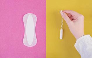 Hygiene care during critical days. Choosing between a tampon and a sanitary pad. Menstrual cycle. The woman holds in hands of a tampon. Top view photo