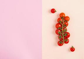 Isolated fresh red cherry tomatoes on pink-beige background. Top view. Flat lay photo