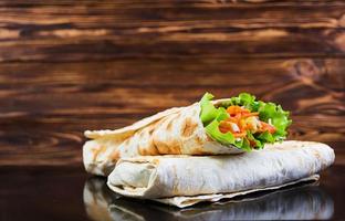 Delicious shawarma sandwich on wooden background photo